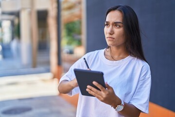 Young beautiful hispanic woman drawing on touchpad at street