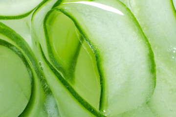 A background of cucumber slices in water. Lots of cucumber slices swirled in water.