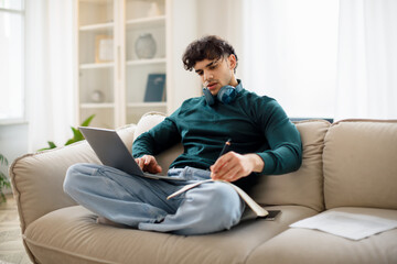 Middle Eastern Guy Studying With Laptop At Home Taking Notes