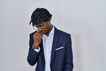 Young african man with dreadlocks wearing business jacket over white background tired rubbing nose and eyes feeling fatigue and headache. stress and frustration concept.