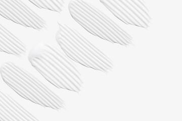 A set of different strokes of white cream on a light background.