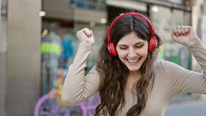 Young beautiful hispanic woman smiling confident listening to music dancing at street
