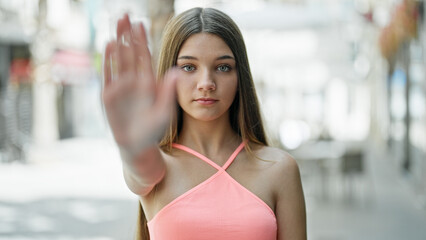 Young beautiful girl doing stop gesture with hand at street