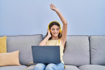 Adorable girl listening to music sitting on sofa at home