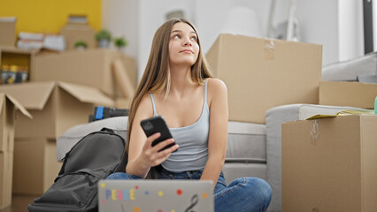 Young beautiful girl student using laptop and smartphone thinking at new home