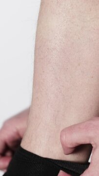 A man pulls and adjusts the elastic band on black socks