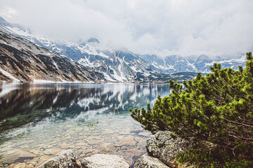 A mountain lake with azure water reflects snow-capped mountains . The Great Polish Lake in Poland.