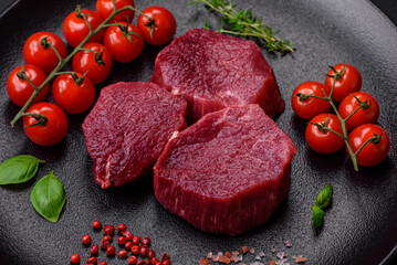 Juicy raw beef with spices, salt and herbs on a dark concrete background
