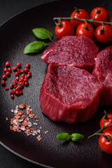 Juicy raw beef with spices, salt and herbs on a dark concrete background