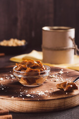 Boiled sweet condensed milk in bowl and spoon on table vertical view