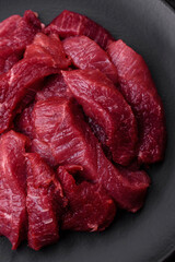 Juicy raw beef with spices, salt and herbs on a dark concrete background