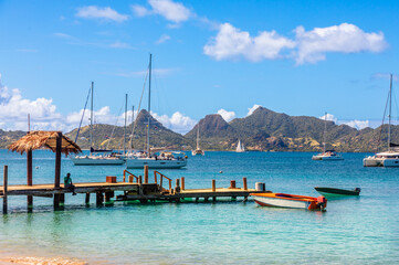 Lagoon with turquoise waters, yachts and boats at Mayreau island pier with Union island in the...
