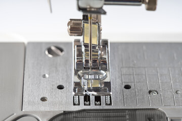 Modern white sewing machine presser foot closeup, macro. Sewing equipment, work tool for atelier business, manufacturing, occupation.