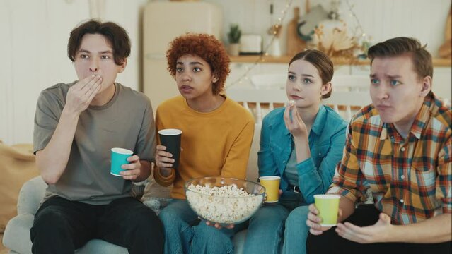 Sports fans friends watch TV sit on sofa at home and cheering for favourite team. They getting upset while team losing, clap hands, high five to support each other. Leisure, hanging together concept.