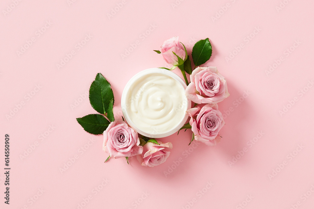 Wall mural jar of moisturizer cream with rose petals on pink background. flat lay, top view.