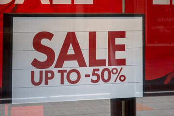 Advertising of the annual period of discounts in the store, information about sale in glass shop window with reflection of people and shopping mall