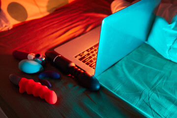 toys for sex on a laptop on a bright neon background. - obrazy, fototapety, plakaty