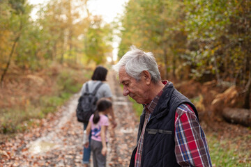 Senior man hiking with his family in autumn forest, shallow depth of field