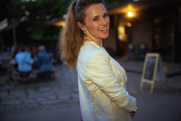Portrait of smiling trendy female in dress and jacket in city
