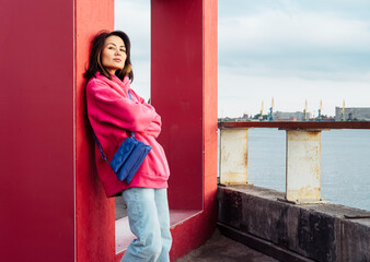 Beautiful stylish Asian young woman in pink sweatshirt, outdoor portrait,