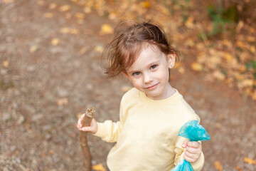 Little girl playing with autumn leaves in the park. Outdoor portrait.