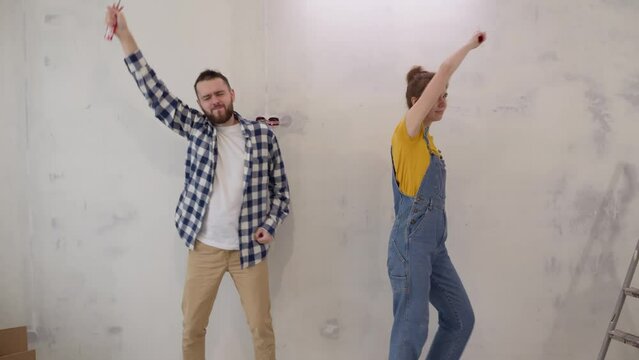Happy young family dancing together with work tools during apartment redecoration and home construction. Renovation and improvement new home. slow motion