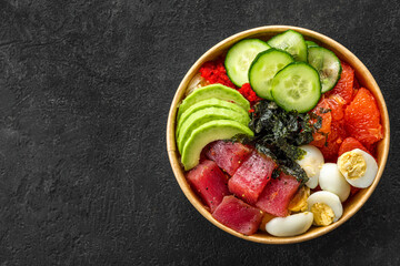 Poke bowl with tuna, avocado, grapefruit, eggs and cucumbers on black background. Top view