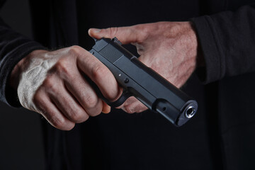 Male hand holding a gun on black background . A gun in a man's hand. defense or attack murderer or armed robber, First person view of a pistol.