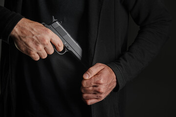 Male hand holding a gun on black background . A gun in a man's hand. defense or attack murderer or armed robber, First person view of a pistol.