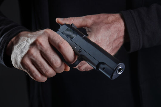 Male hand holding a gun on black background . A gun in a man's hand. defense or attack murderer or armed robber, First person view of a pistol.