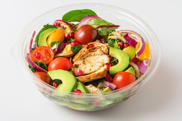 Healthy chicken salad with avocado, tomatoes and pomegranate in plastic package for take away or food delivery