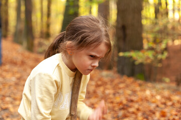 Little girl playing in the autumn forest. Selective focus on the girl