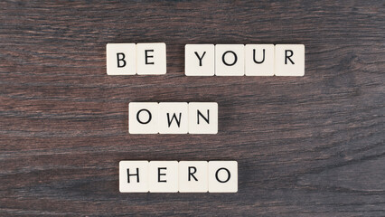 Be your own hero word on white stones. Motivational quote concept. Motivational words on little white stones on wooden table. High angle view