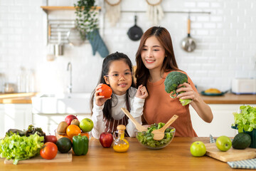 Portrait of enjoy happy love asian family mother and little asian girl daughter child having fun help cooking food healthy eat together with fresh vegetable salad and ingredient in kitchen