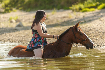 Equestrian and horse cooling down at a hot summer day: A young woman and her bay brown andalusian x...