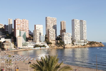 Edificios al final de la playa con dos torres gemelas blancas sobre el mar. 