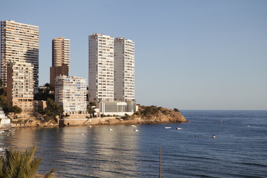 Edificios al final de la playa con dos torres gemelas blancas sobre el mar. 