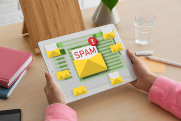 Spam warning message, envelope illustrations popping out of device display. Woman using email software on tablet computer at table, closeup