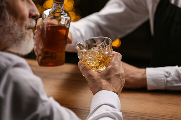 Bartender pouring whiskey in glass for customer at bar counter, closeup
