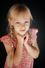 portrait of a girl with pigtails in a summer red dress, a photo session of a child on the street