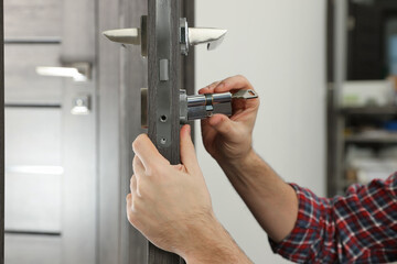 Handyman changing core of door lock indoors, closeup