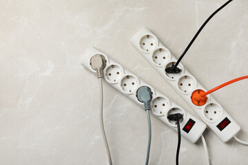 Power strip with extension cords on grey marble table, flat lay. Space for text