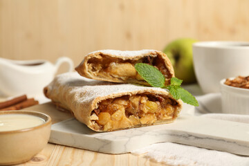 Delicious strudel with apples, nuts and raisins on wooden table, closeup