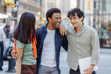 Multiracial young people talking on street near university campus smiling. Planning startup together