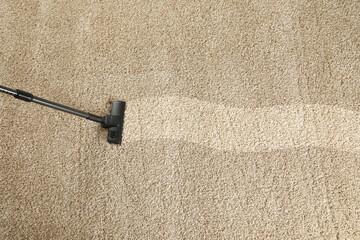 Hoovering carpet with vacuum cleaner, above view and space for text. Clean trace on dirty surface