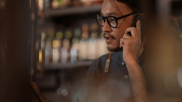 Night club concept of 4k Resolution. The bartender is taking orders from customers with the phone in the restaurant. A group of specialized clubs that sell alcoholic beverages.