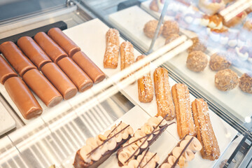A variety of cakes covered with chocolate and decorated with pistachio mousse. A showcase in a pastry shop with delicious desserts with fresh berries and cream. Delicious pastries in the coffee shop.