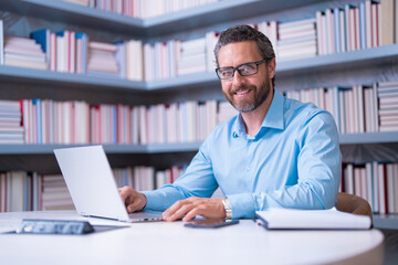 Portrait of teacher with book in library classroom. Handsome teacher in university. Teachers Day. Good school teacher. Tutor at college. Man with books in library. Knowledge and education concept. - obrazy, fototapety, plakaty