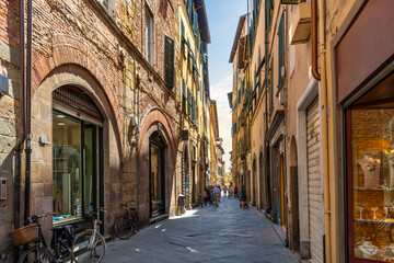 A picturesque narrow alley or street of shops, businesses and apartments in the historic center of Lucca, Italy in the Tuscany region.