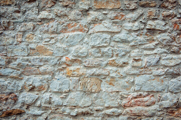 The background of an old brick wall covered with white plaster close up. Texture of white orange brick, light brick background